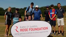 Children pose in front of a kate and justin ROSE FOUNDATION banner on a golf course