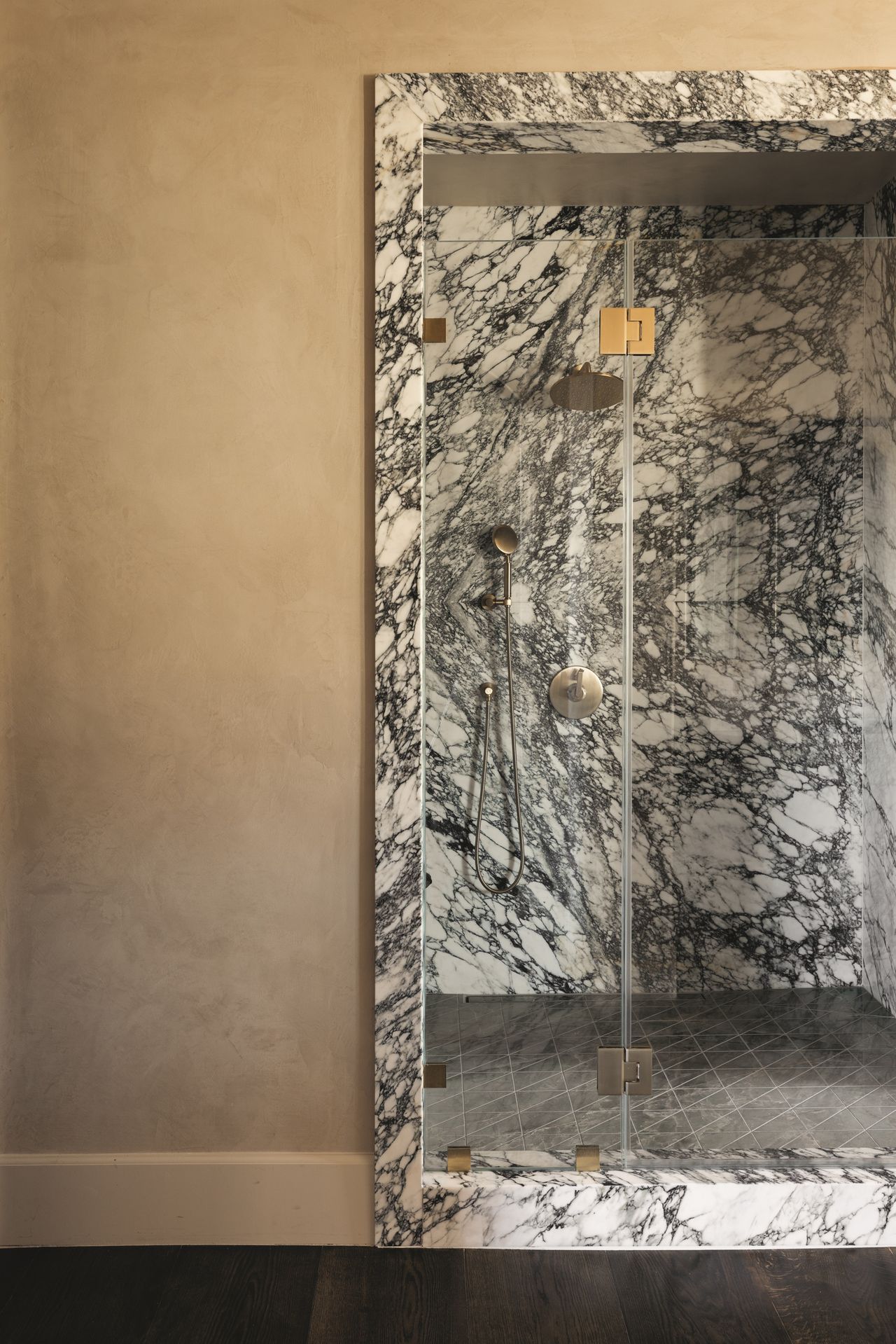 modern marble bathroom enclosure with beige plaster walls outside and timber flooring