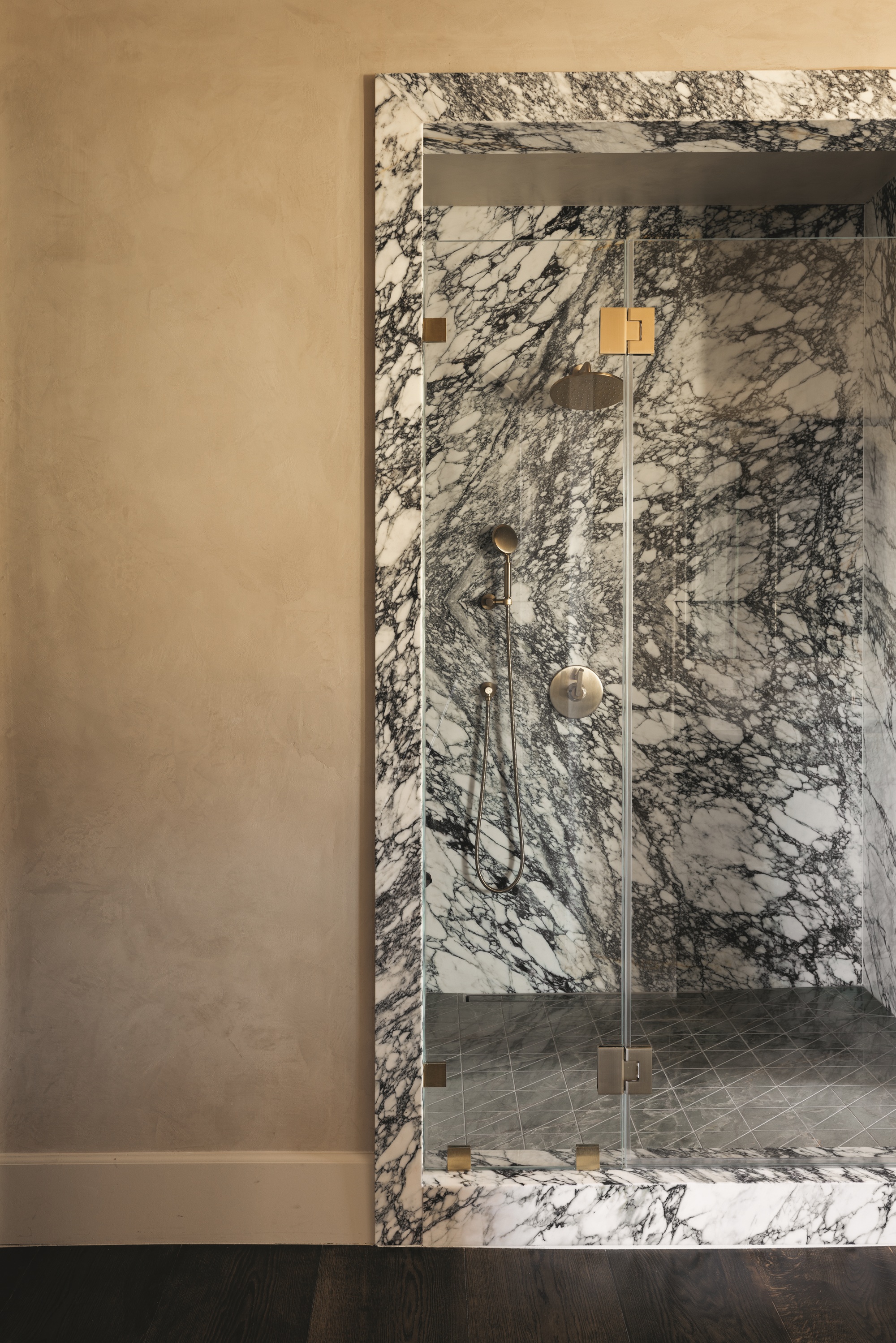 modern marble bathroom enclosure with beige plaster walls outside and timber flooring