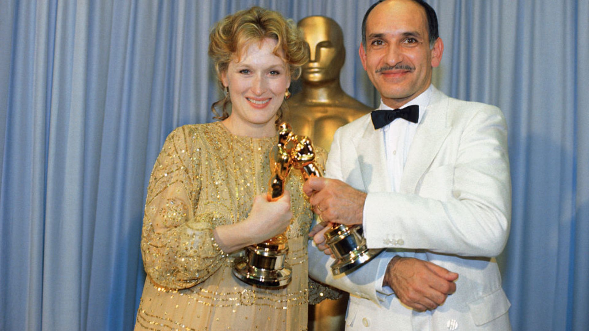 Meryl Streep wearing a floaty golden gown touches Oscars with Ben Kingsley who won the Best Actor award for his portrayal of Ghandi