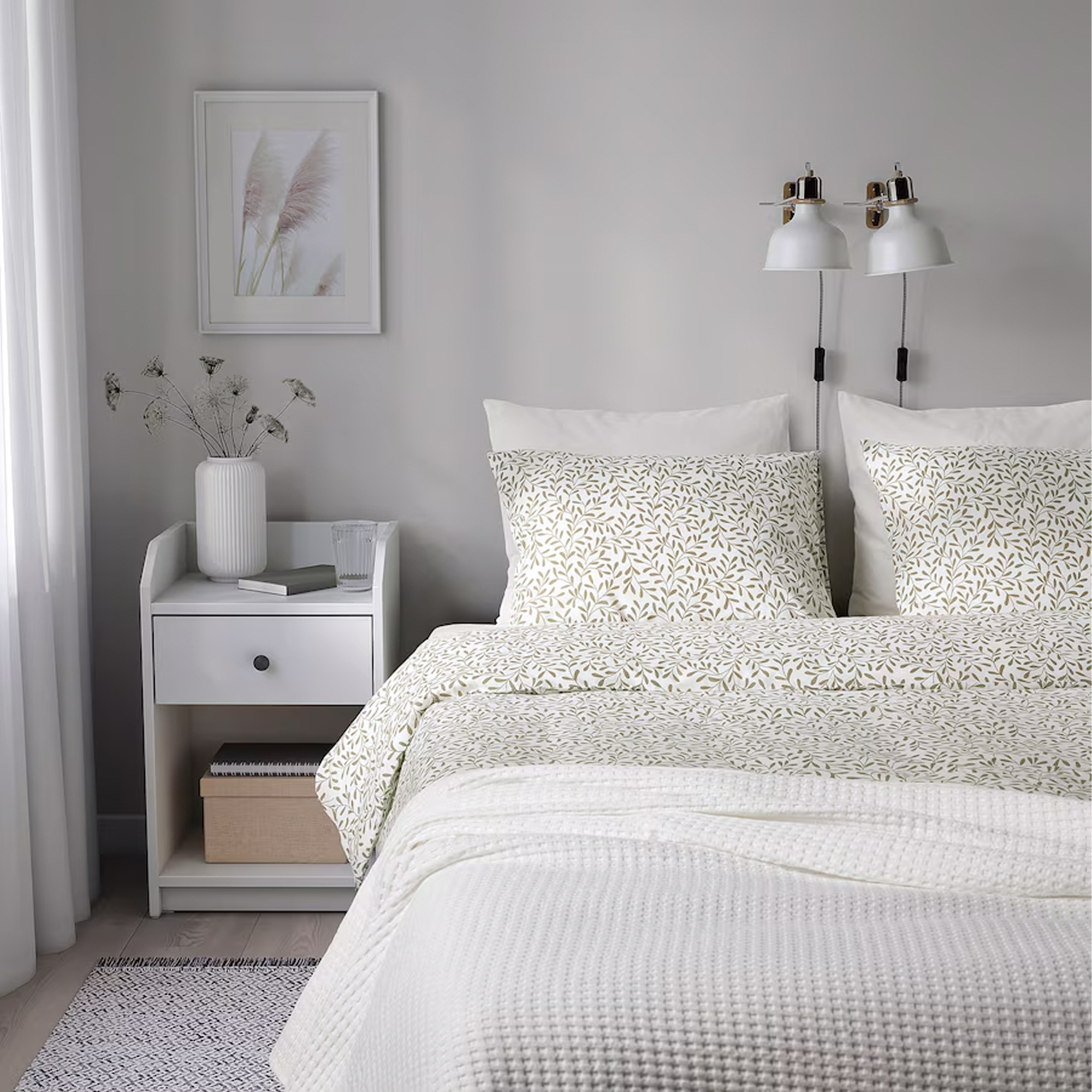 A white bedroom with a bed dressed in an IKEA duvet set with a leaf pattern