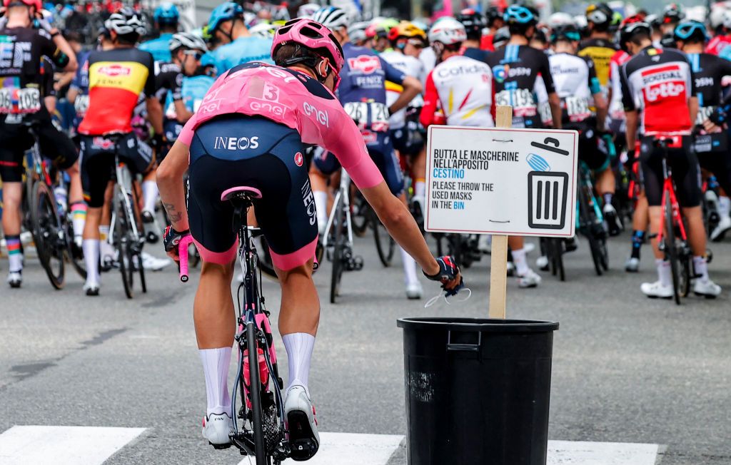 TOPSHOT Team Ineos rider Italys Filippo Ganna wearing the overall leaders pink jersey throws away his face mask in a bin prior to the start of the second stage of the Giro dItalia 2021 cycling race 179 km between Stupinigi and Novara on May 9 2021 Photo by Luca Bettini AFP Photo by LUCA BETTINIAFP via Getty Images