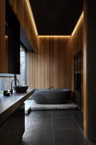 bathroom with black tiles and timber walls