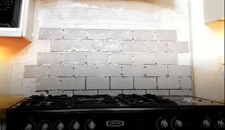 a kitchen wall being tiled