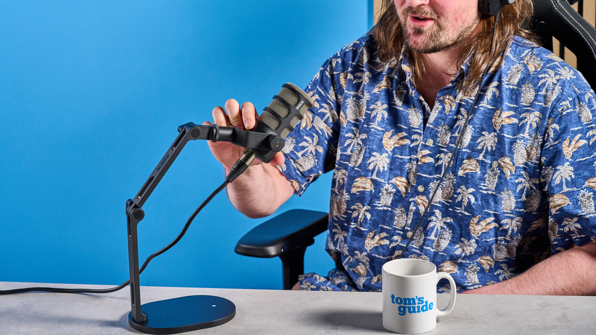the rode podmic podcast and broadcast microphone photographed with a blue background, shown with the rode ds2 desk stand