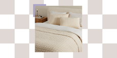 bed made with quilted bedding in a soft yellow color with four pillows