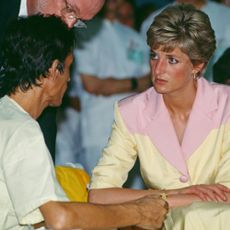 Princess Diana wearing a yellow and pink suit talking to a man at a hospital