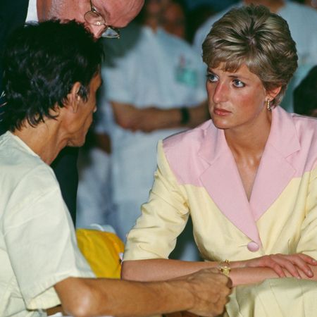 Princess Diana wearing a yellow and pink suit talking to a man at a hospital