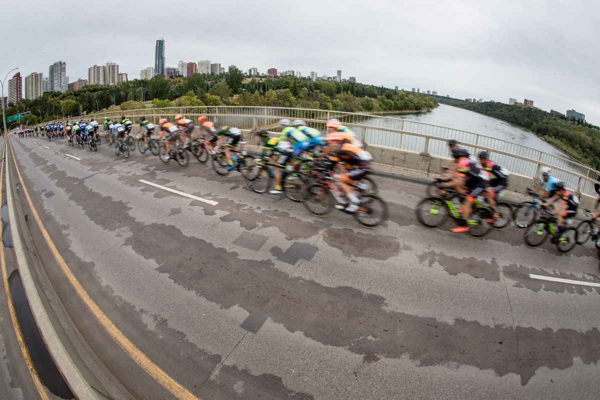 The peloton crosses a bridge with Edmonton in the background