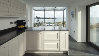 white kitchen peninsula with views through full height glazing