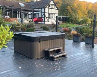 Anthracite grey composite decking board with hot tub decor in back garden
