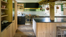 wooden kitchen with large central island, black countertops, and a traditional range cooker 