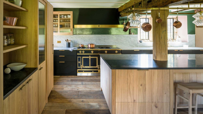 wooden kitchen with large central island, black countertops, and a traditional range cooker 