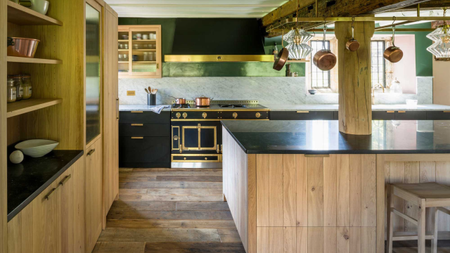 wooden kitchen with large central island, black countertops, and a traditional range cooker 