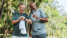 Two older men smile as they get some exercise together outside.
