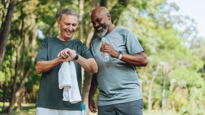 Two older men smile as they get some exercise together outside.