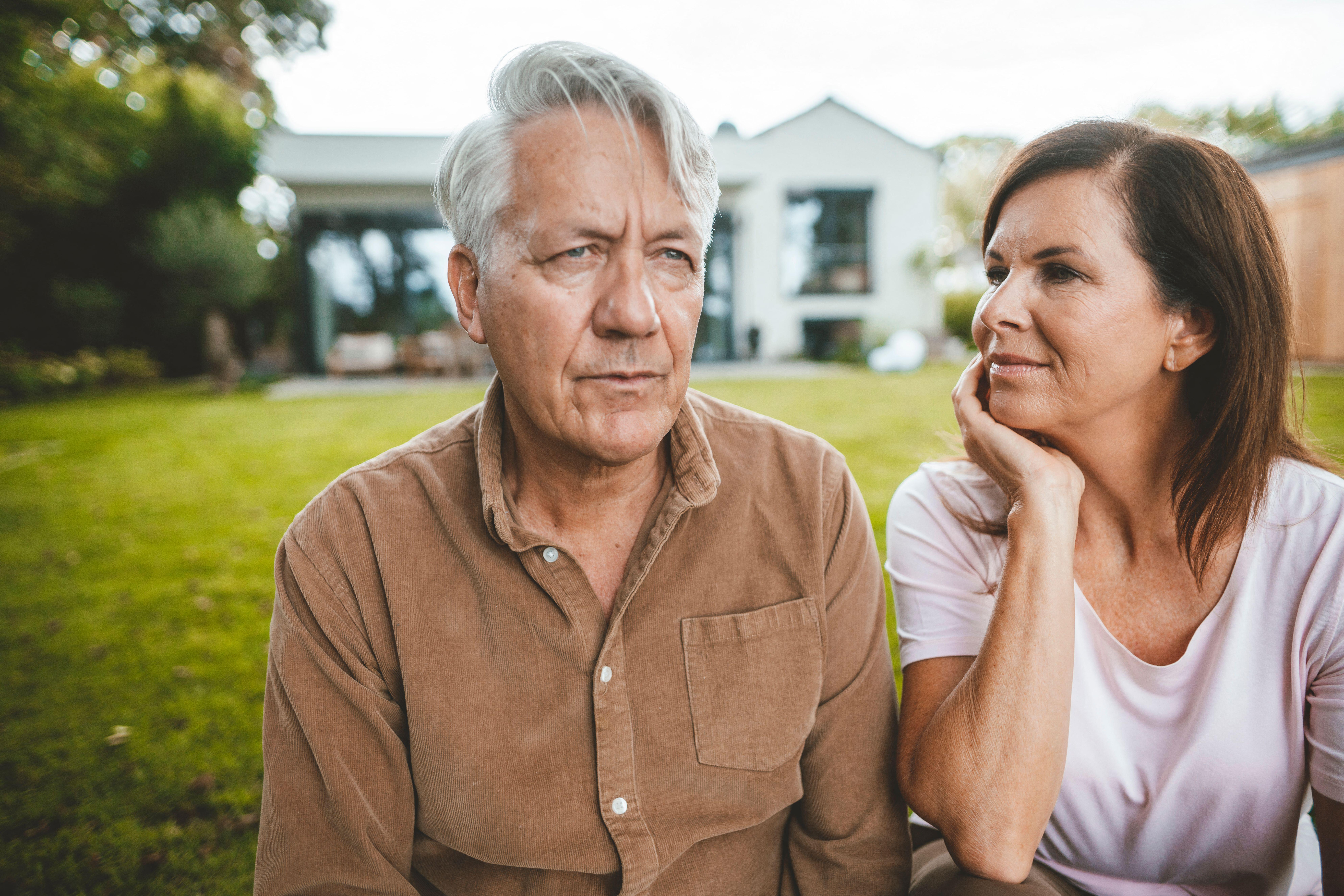 2HWR61B Woman with hand in head looking at man with white hair at backyard