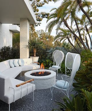 Outdoor terrace with sofa fire pit and white iron chairs