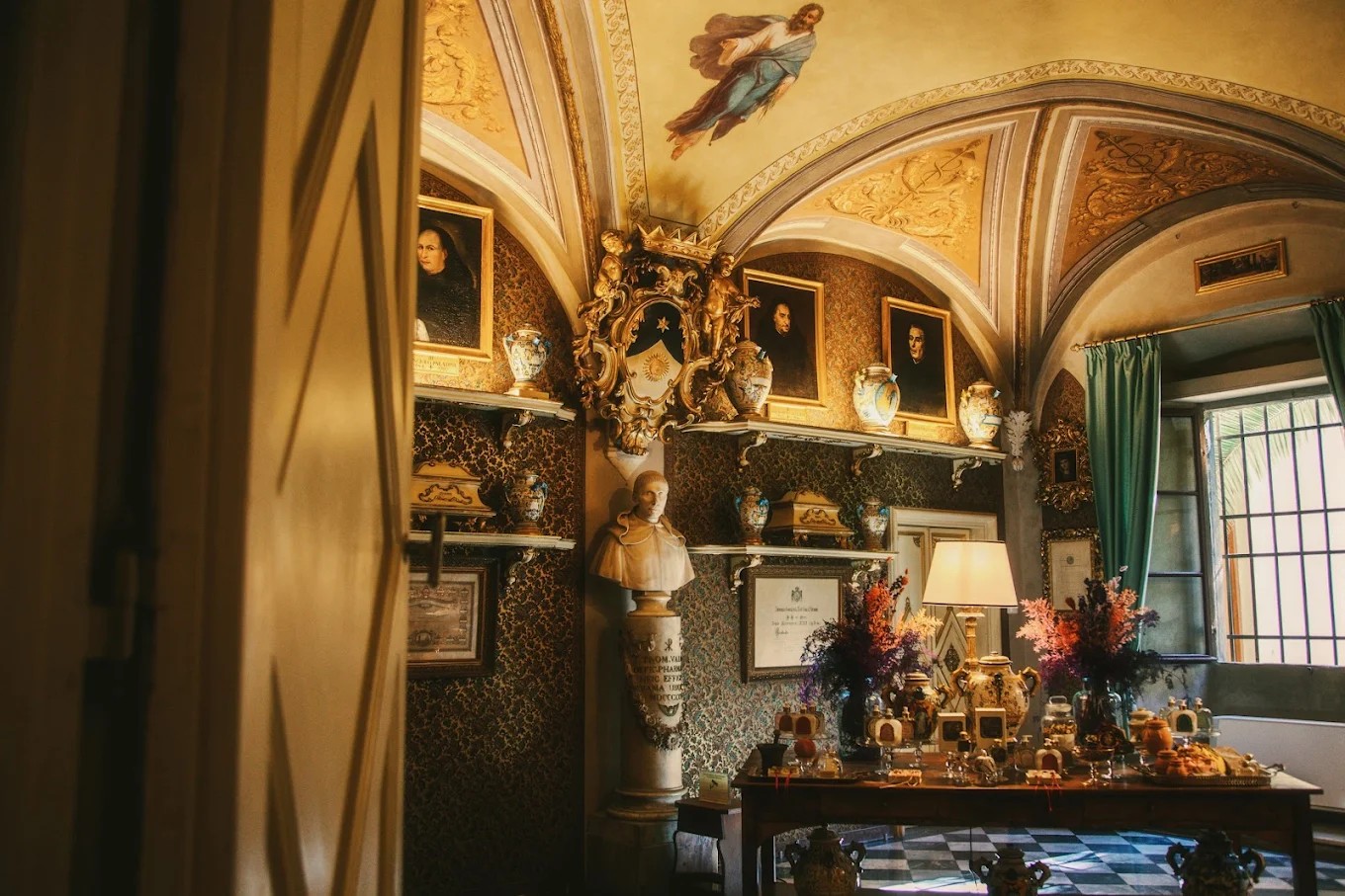 A golden-lit room with ornate, vaulted ceilings houses a series of quirky, historical collectibles, including gold leaf-framed portrait paintings, warmly glowing lamps, and marble busts.