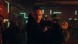 A promotional still from the film Havoc which shows Tom Hardy restraining a thug in a nightclub.