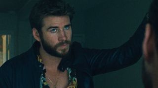 Liam Hemsworth leans against a door in 'Killerman'