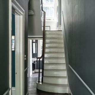 A hallway painted in Farrow & Ball with bare wooden stairs painted white