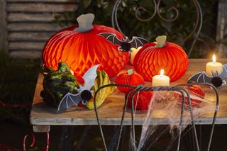A Halloween tablescape with paper pumpkins, candles and foliage