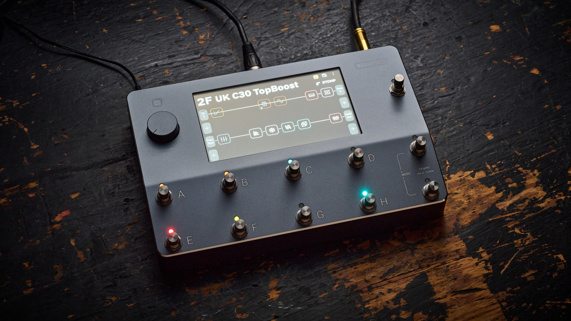 A Neural DSP Quad Cortex multi-effects pedal lying on a worn, wooden floor