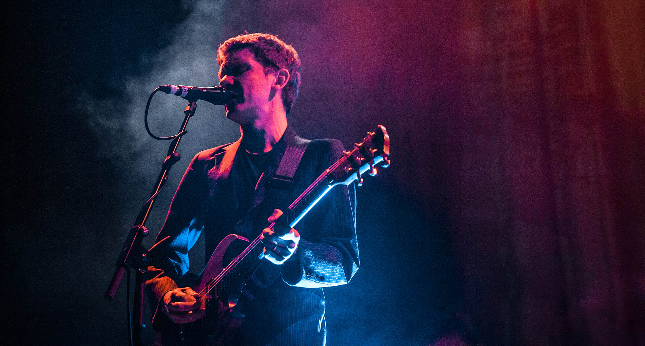 Peter Brewis of Field music is bathed in pink and blue lights as he performs live