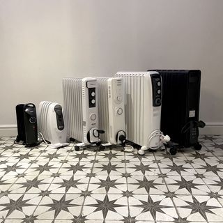 A group of six oil filled radiators being tested in a home with a black and white geometric tiled floor