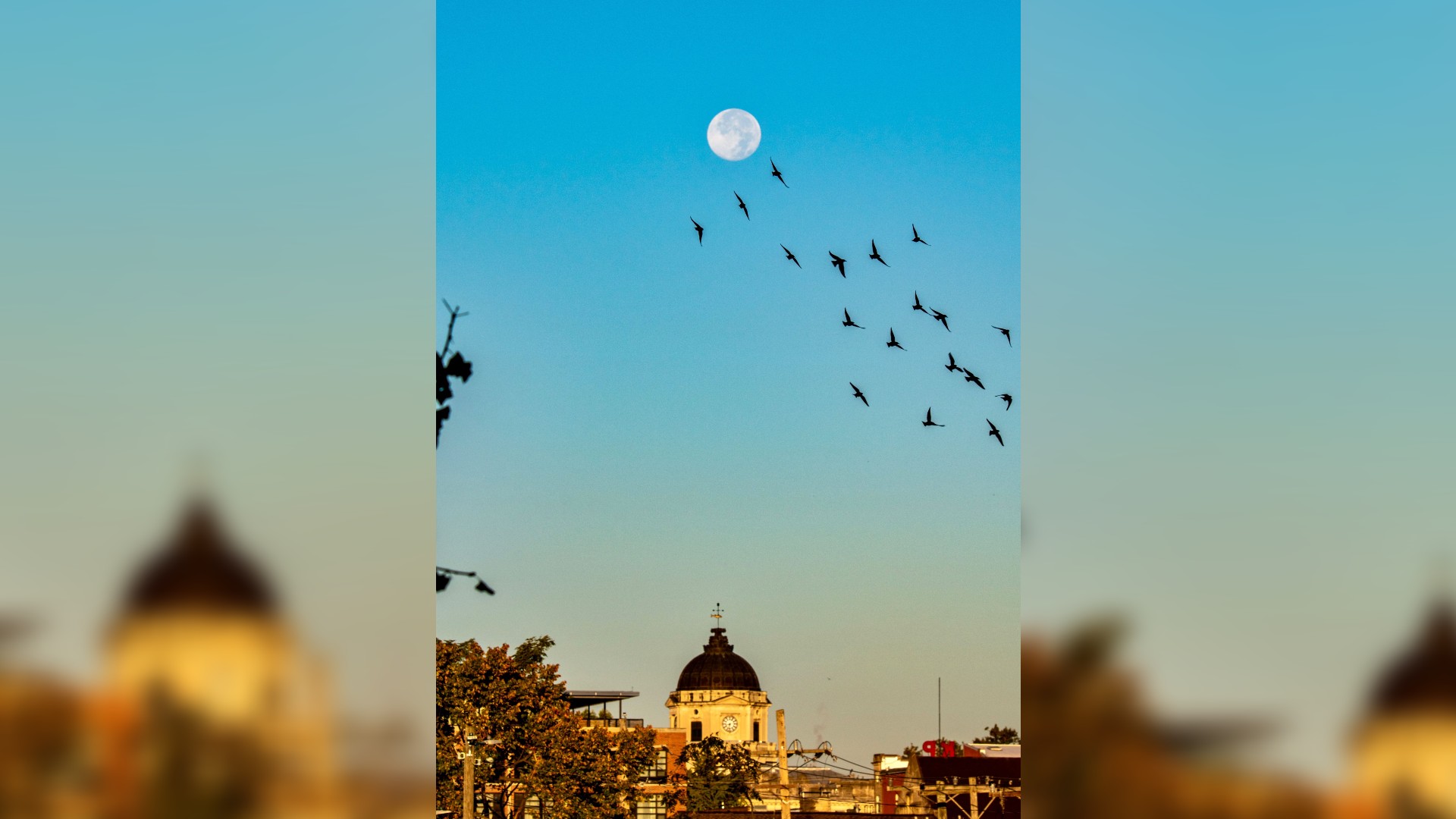 la pleine lune se lève sur les bâtiments dans un ciel bleu clair