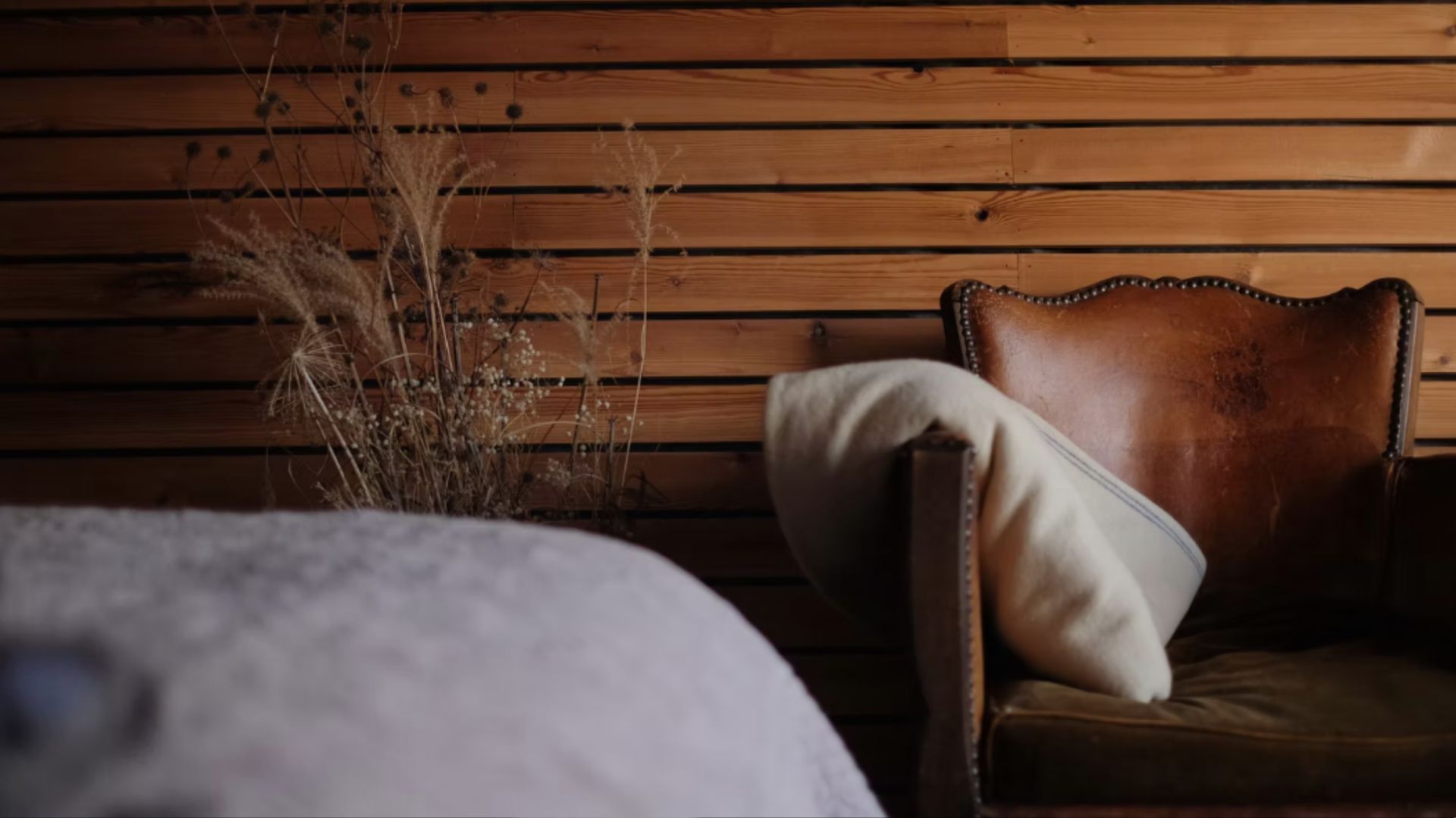 A leather chair in the Hergest Lee Cabin with the end of the bed throw in the corner