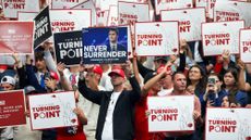 Attendees hold up signs during the memorial service for Charlie Kirk