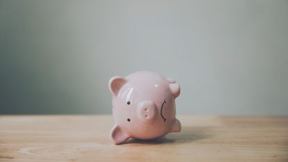 A piggy bank with a sad face lies on its side.