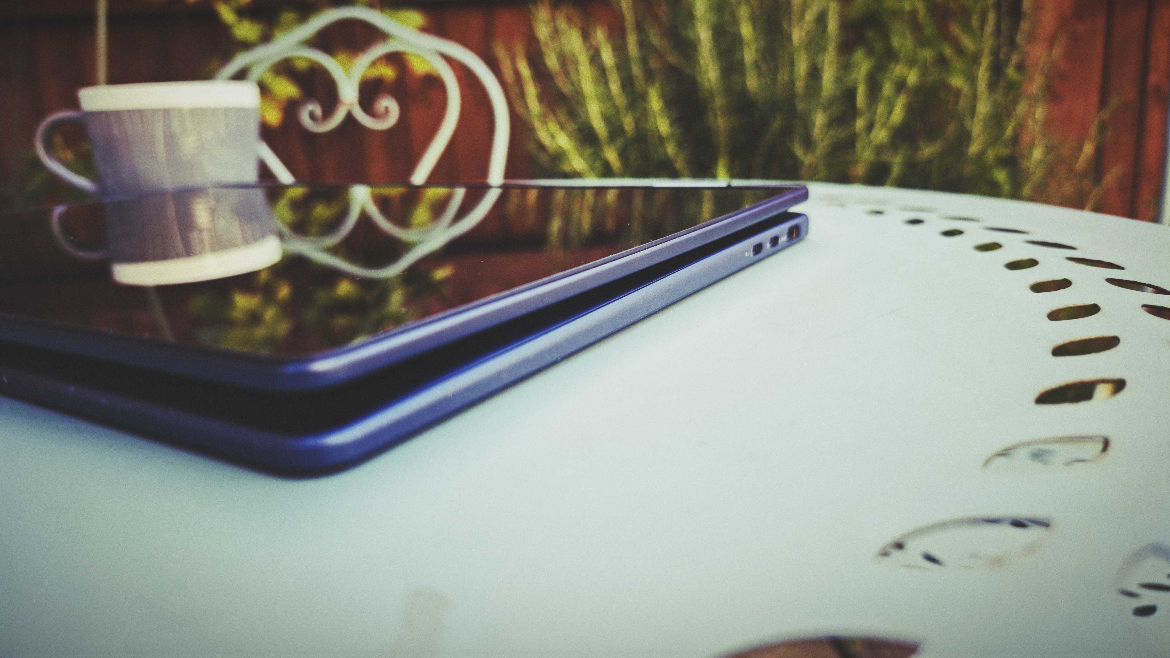 A Dell 16 Plus 2-in-1 laptop on a blue garden table
