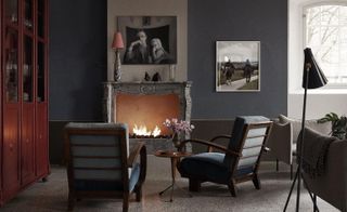 Two grey armchairs in front of grey marble fireplace, Granite floors and wooden wall unit
