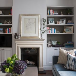 A living room with bookcases in the alcoves with the back of the shelves painted in a darker, contrasting shade of grey