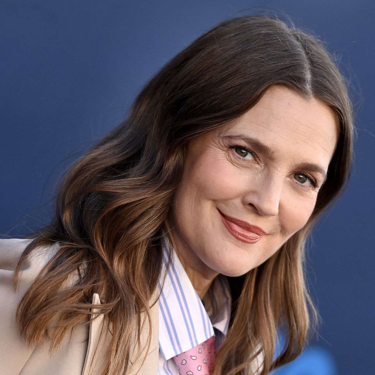 Drew Barrymore wearing suit in front of blue background