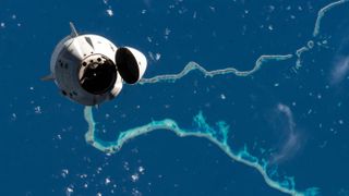 The Crew Dragon capsule Endeavour with four astronauts aboard is departing the International Space Station against a backdrop of Pacific coral atolls.