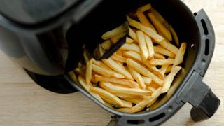 An open air fryer basket from above filled with French fries