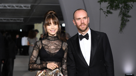 Actress Lily Collins wearing a black lace dress and husband Charlie McDowell wearing a tuxedo at a gala event in 2022