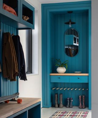 hallway with bold blue open cupboard and matching wall panelling and wooden seat with storage below