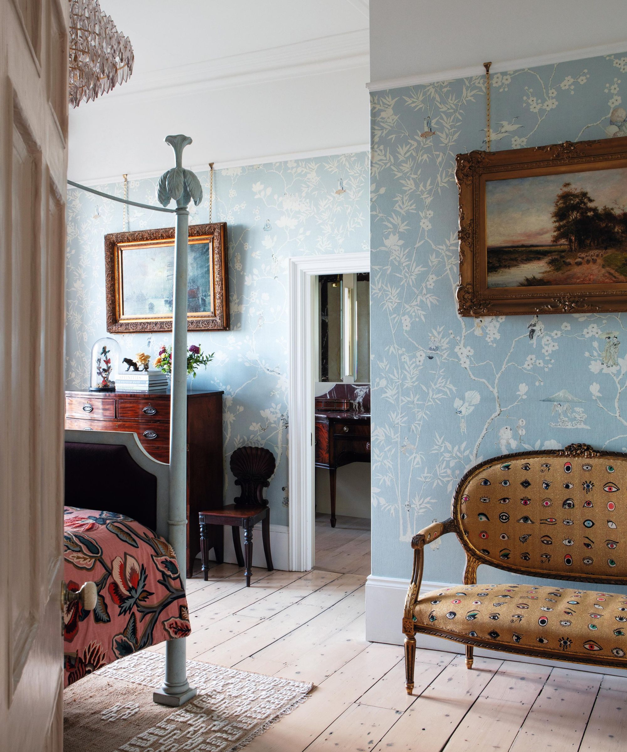 a master bedroom with blue floral wallpaper, high veiling and a blue four poster bed