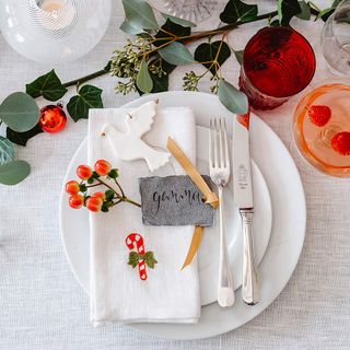 White tablelcoth on dining table with decoration and orange berries on place setting