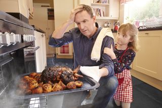 Man takes burnt turkey from the oven.