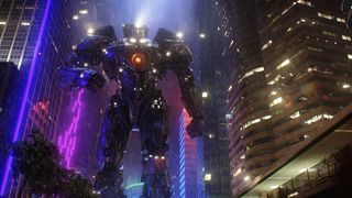 En stillbild på en enorm robot i Pacific Rim, som patrullerar bland höghusen i en storstad.