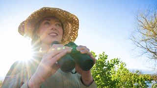 Nikon Prostaff P3 8x42 binoculars being held by a young woman wearing straw hat outdoors