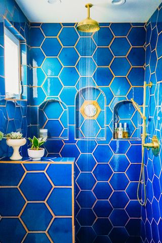 Gold glimmers in a shower tiled in royal blue