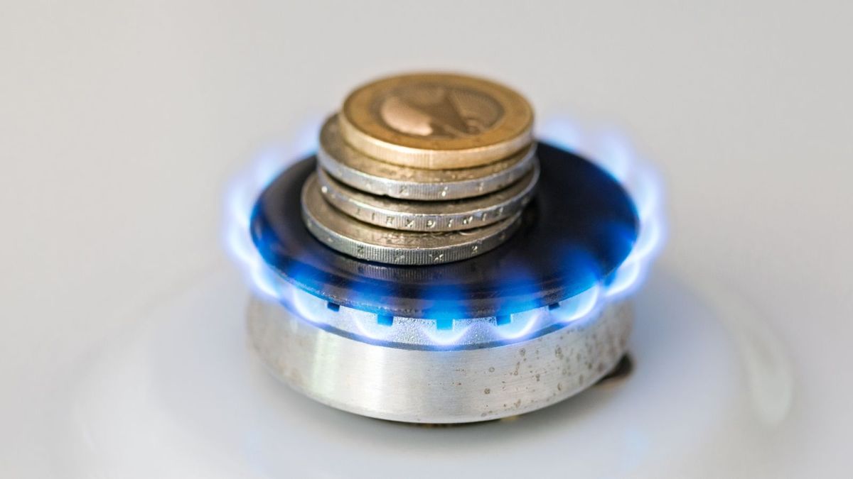 A lit gas burner burns money with a blue flame - Concept illustrating rising gas prices