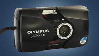 The Olympus Mju II camera on a blue background
